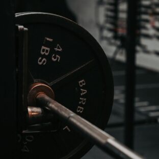 Close-up of a barbell shaft and a mounted plate marked 45 LBS in a gym rack.