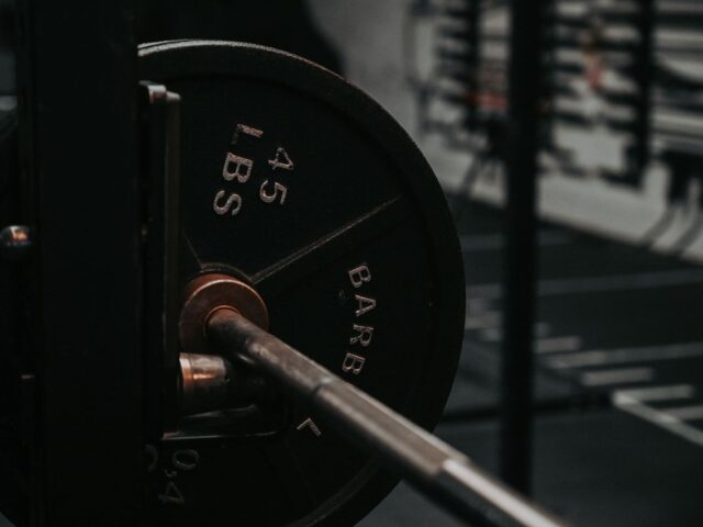 Close-up of a barbell shaft and a mounted plate marked 45 LBS in a gym rack.
