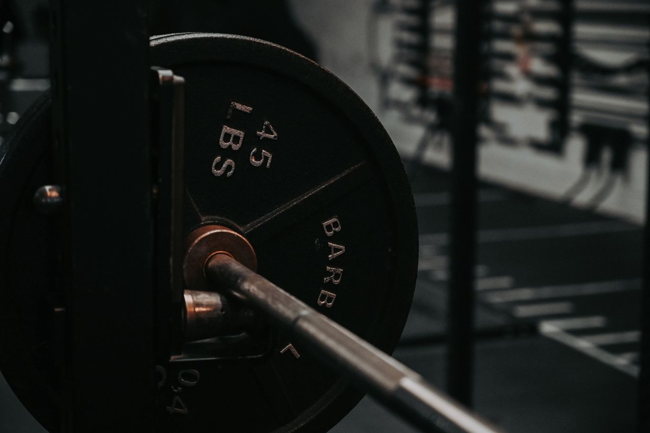 Close-up of a barbell shaft and a mounted plate marked 45 LBS in a gym rack.