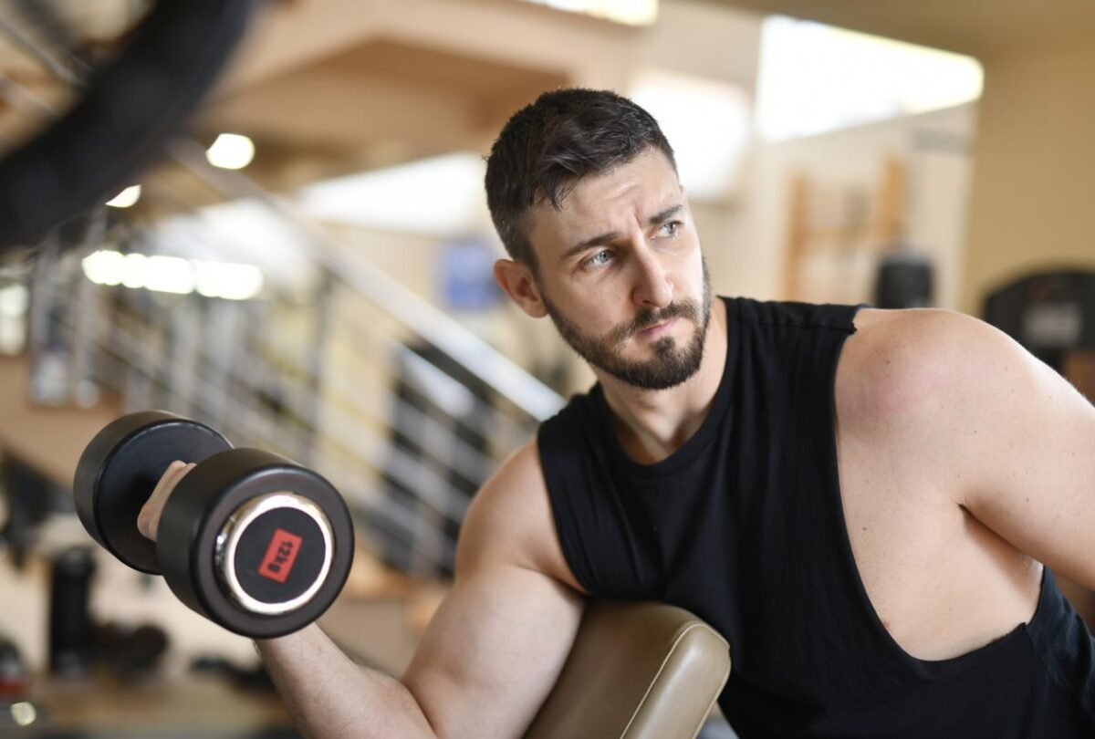 Man performing a dumbbell curl with his upper arm supported on a preacher bench