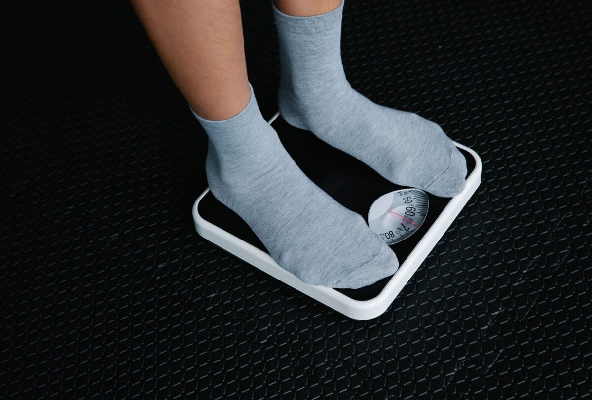 Gray-socked feet standing on a black-and-white analog bathroom scale.