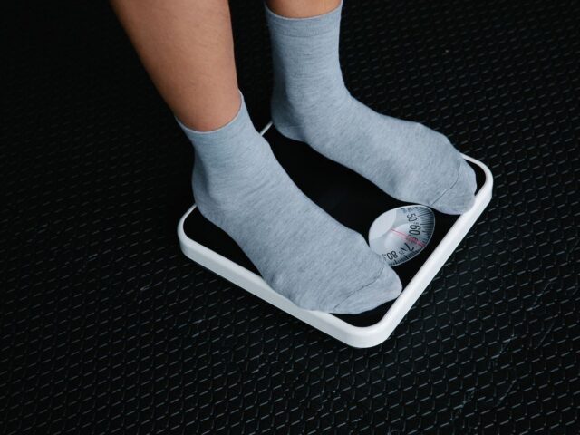 Gray-socked feet standing on a black-and-white analog bathroom scale.